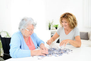 A woman works on a puzzle with her mom, one of many senior activity ideas to make each day more enjoyable.