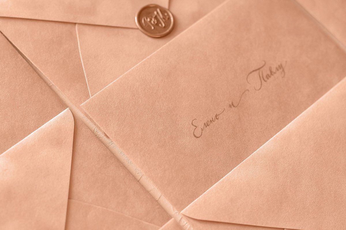 Peach wedding envelope addressed by hand in calligraphy and closed with a wax seal, showing how to address wedding invitation envelopes