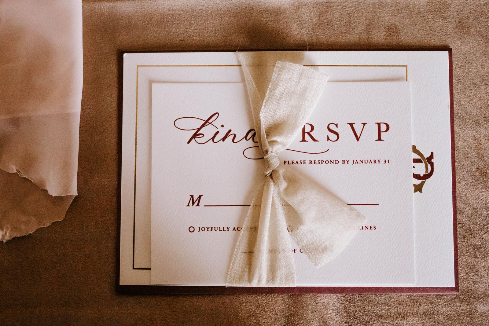 Wedding RSVP reply card printed with a response-by date and tied with ribbon