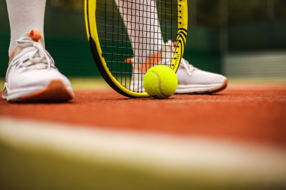 Person in white sneakers playing tennis 