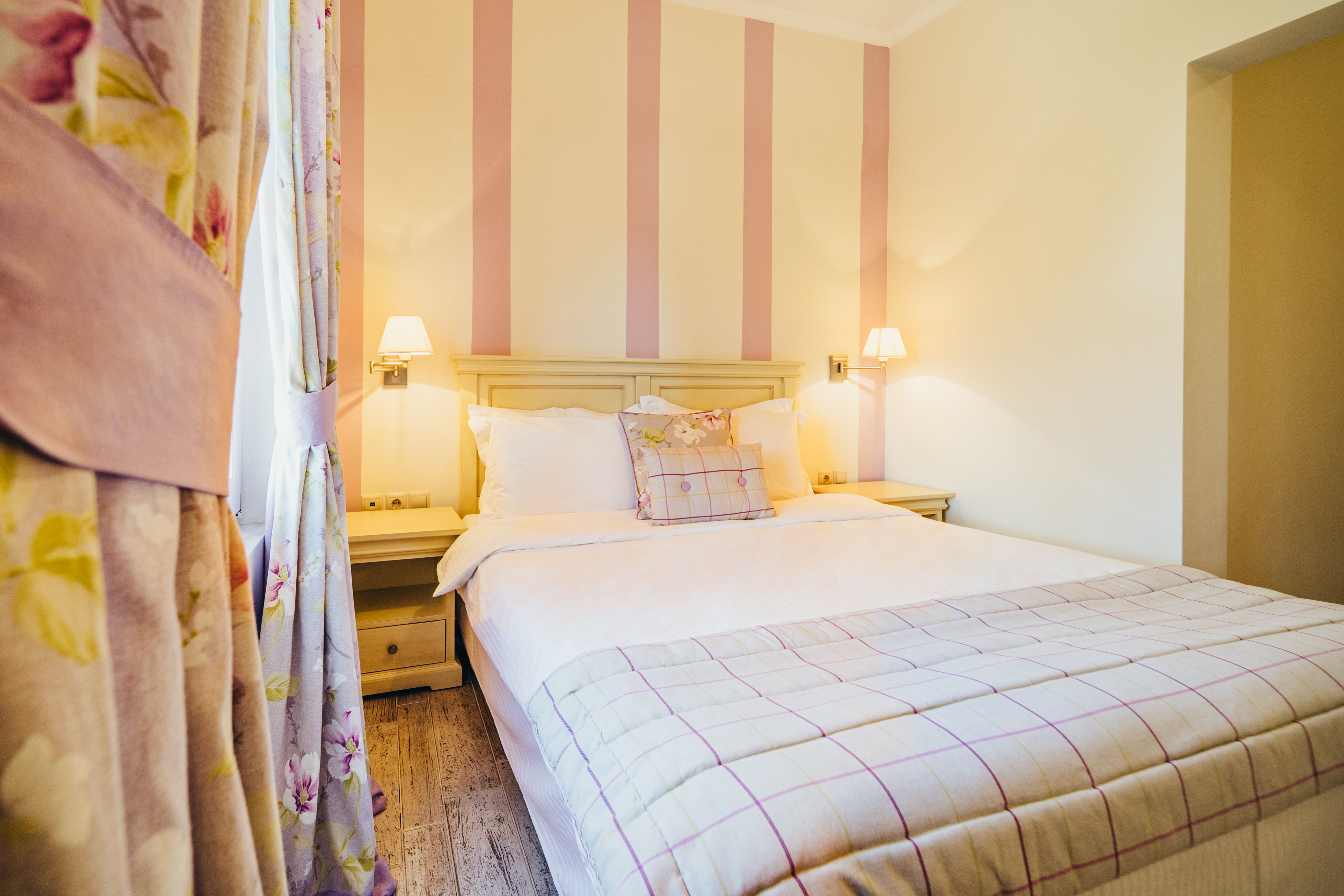 Double bed in deluxe purple room with curtains and warm lighting