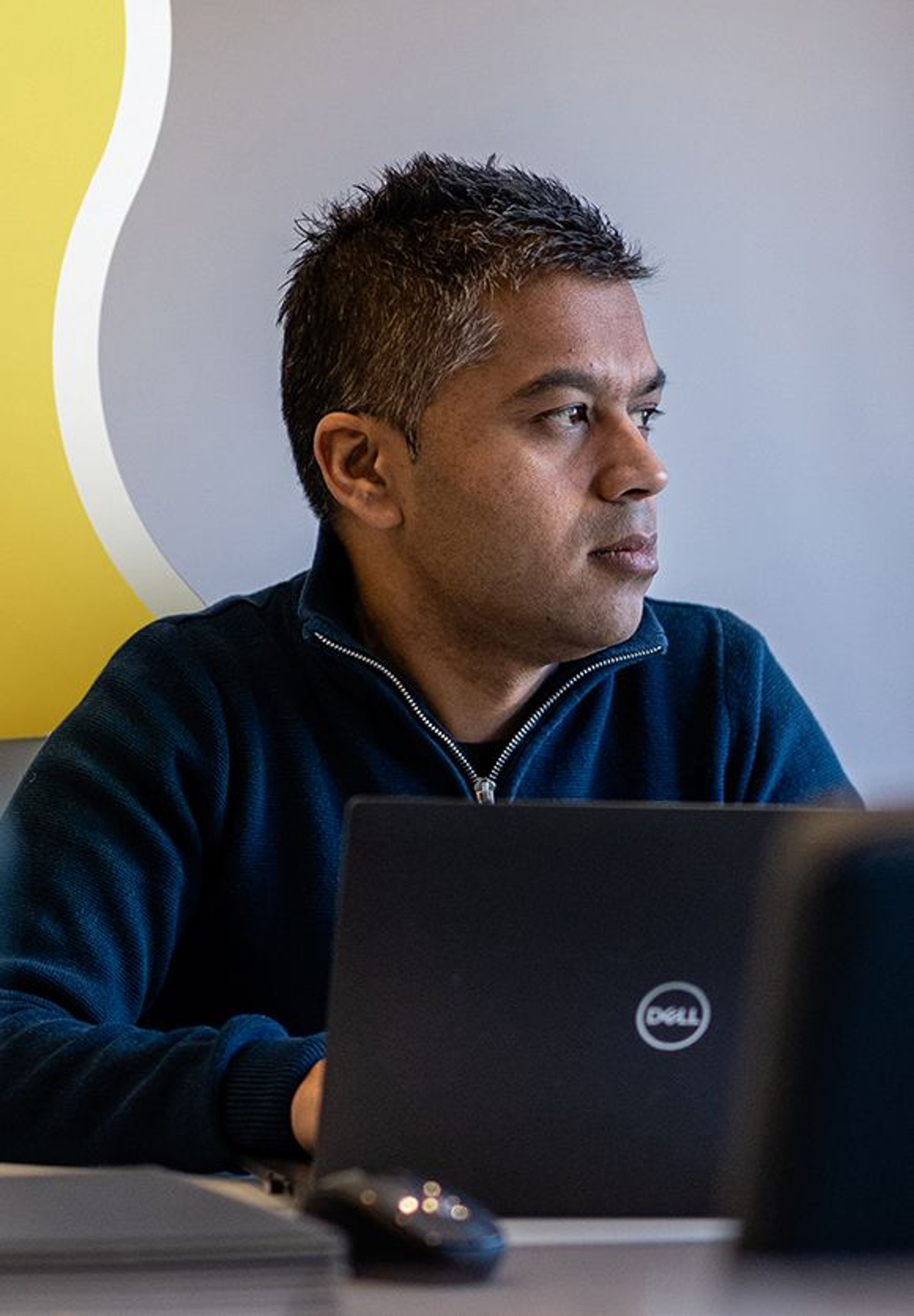 A kidney patient in a room with his laptop staring into the distance. Behind him is a giant yellow kidney with the words 'the big topic everyone's ignoring' within it