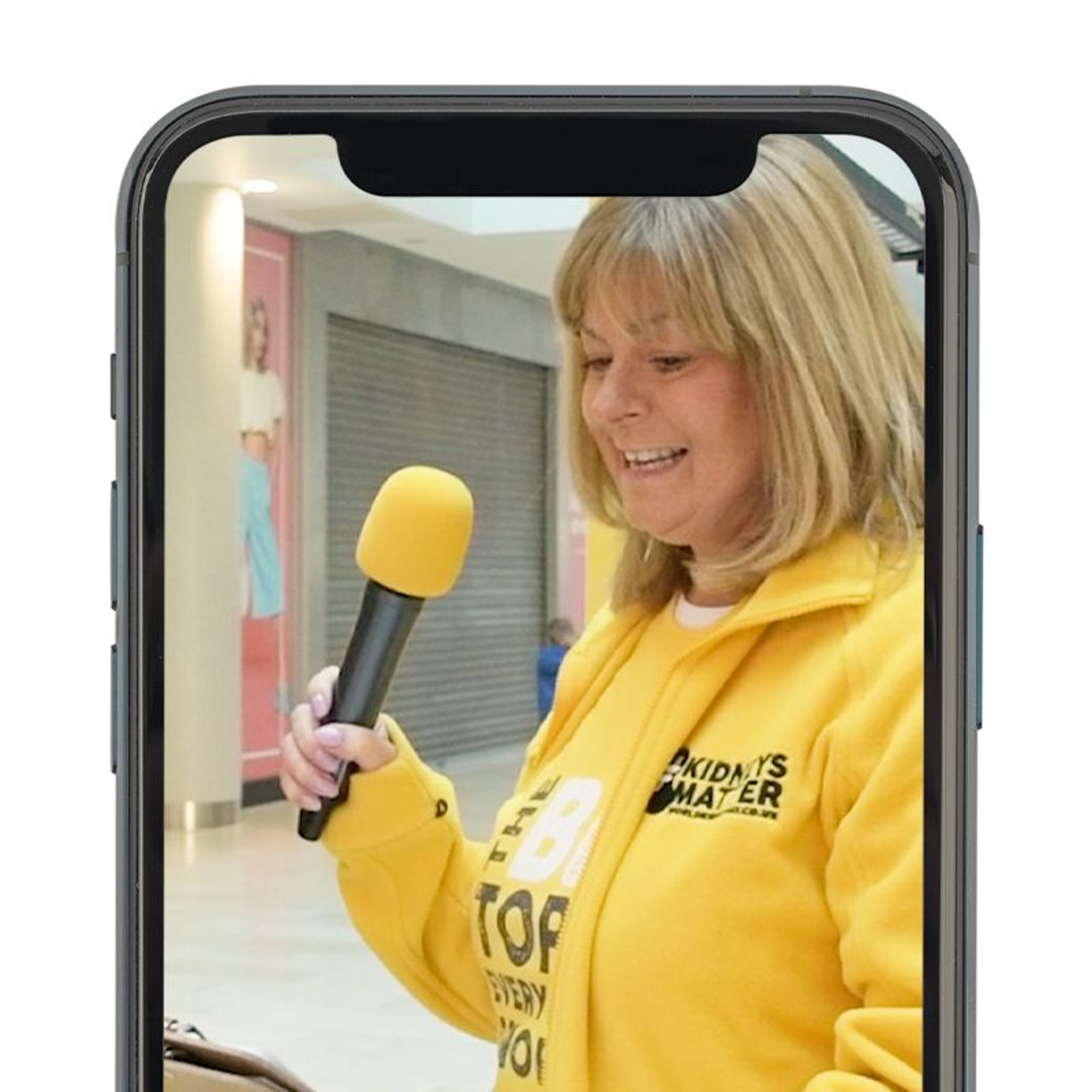 A mobile device showing a video of a volunteer with a mic and clipboard in World Kidney Day apparel