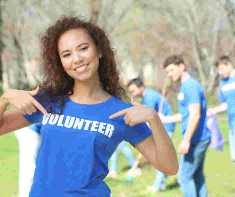 young volunteer pointing to their blue tshirt with 'volunteer' on
