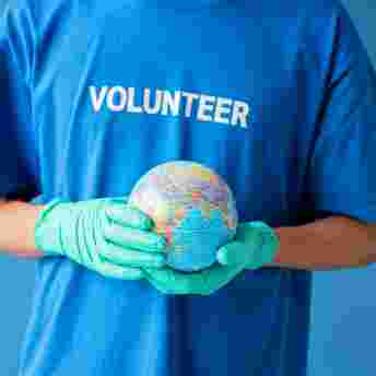 Volunteer in blue t-shirt holding a small globe of the earth