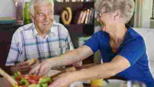 Twee ouderen die samen genieten van een warme maaltijd
