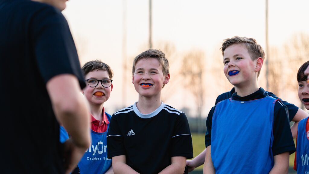Jongens met hockey-bitje kijken naar  een trainer