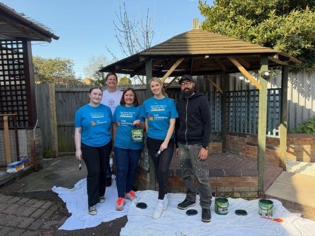 Photo shows five people in blue t shirts next to a pagoda 