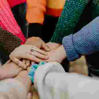 A group of hands meeting in the centre of a circle
