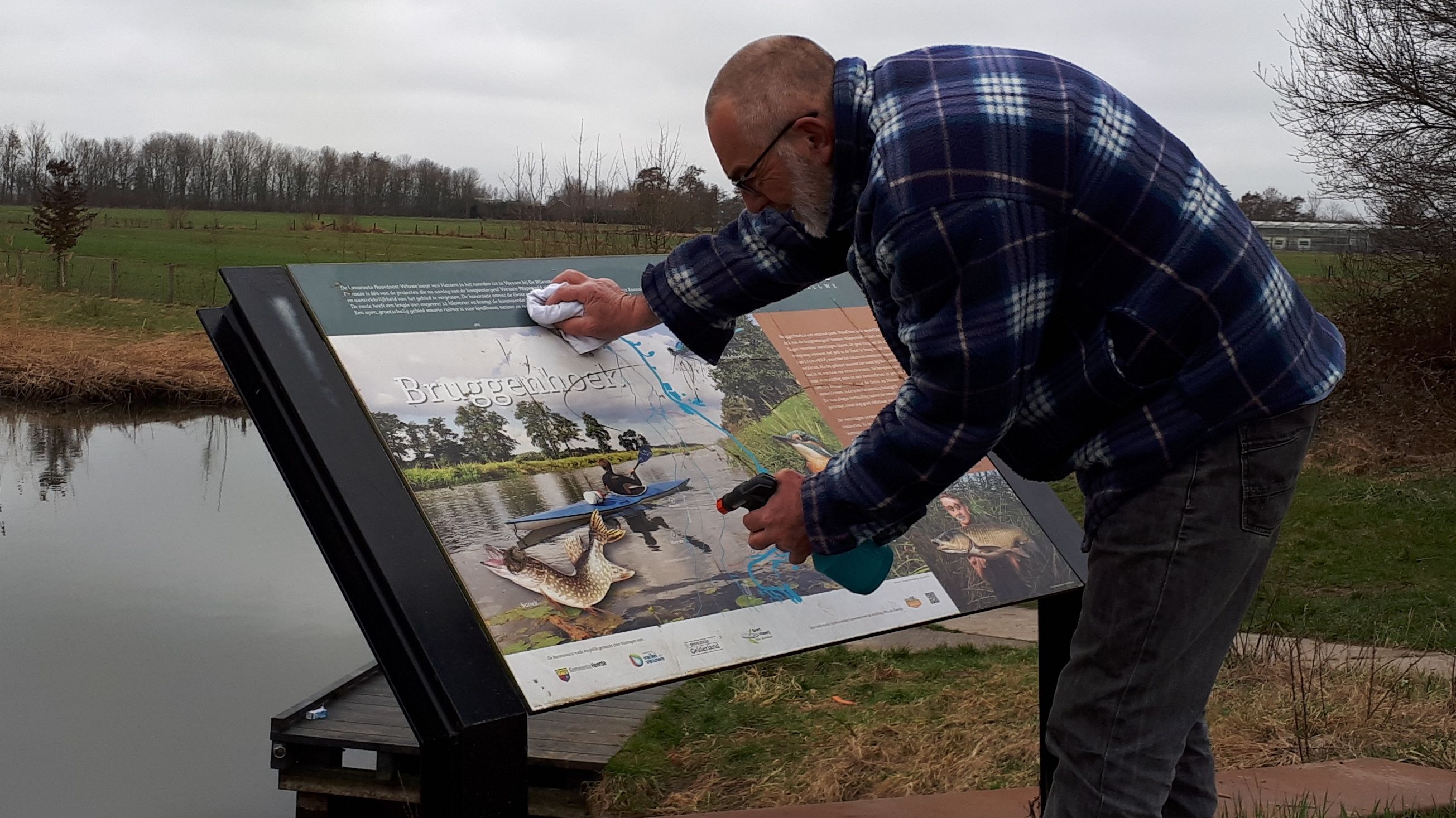 Gerrit, vrijwilligerscoördinator van het Paddenpad maakt een informatiebord schoon