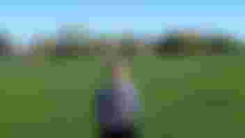 Young lady standing in a field looking at the camera.