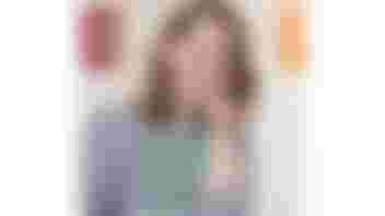 The photo shows Hannah smiling, she has brown shoulder length hair and is wearing a striped black and white top and a green lanyard.