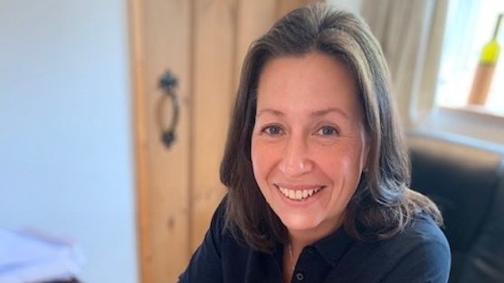 Woman with brown hair who is smiling and wearing a blue shirt.