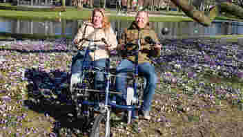 Fietsmaatjes Apeldoorn en Omstreken gaat van start. Vrijwilligers stappen met gasten op de duofiets voor een ritje.