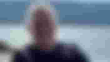 Photograph of Anthony, sat down, smiling at camera.