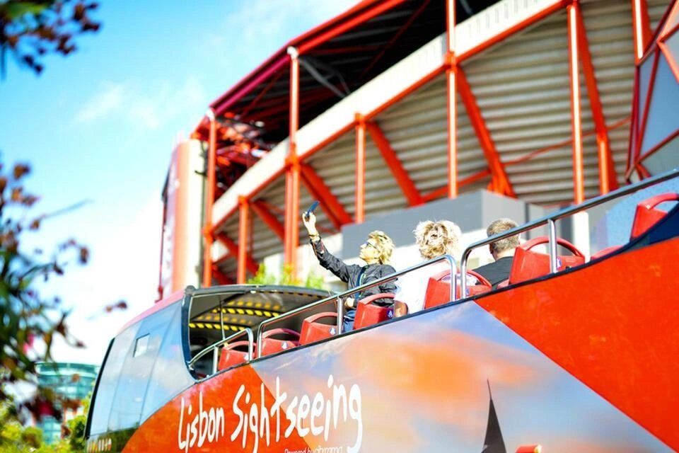 open-top red double-decker bus during a Lisbon Sightseeing Hop-On, Hop-Off Tour passing by a stadium 