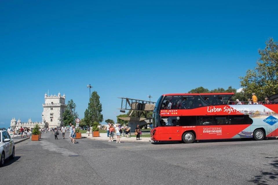 double-decker open-top sightseeing bus operated by Gray Line parked near the historic Belém Tower 