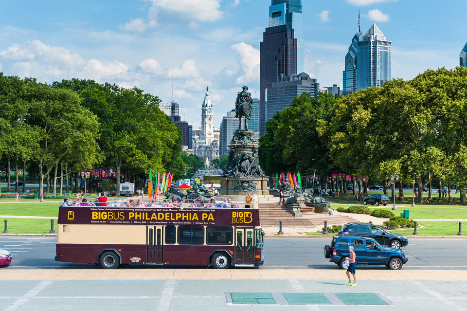 Big Bus Philadelphia double-decker sightseeing tour bus traveling along the Benjamin Franklin Parkway near Eakins Oval, with the Philadelphia