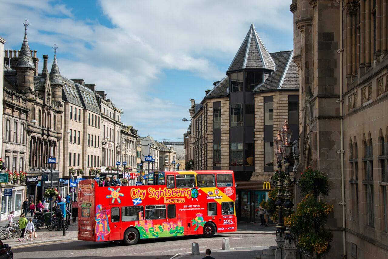 City Sightseeing open-top double-decker hop-on hop-off tour bus navigating a street in Inverness