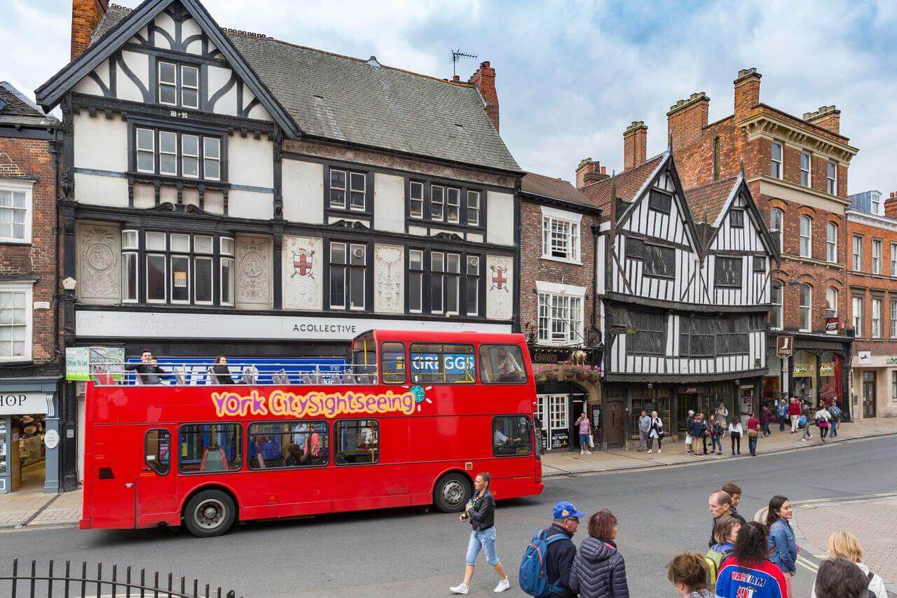 sightseeing tour bus traveling along Pavement street in the historic city center of York, England