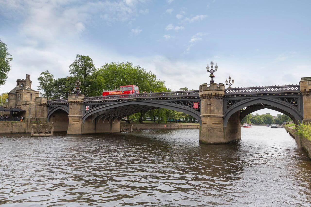 Skeldergate Bridge crosses the River Ouse in York, England, featuring a red sightseeing bus