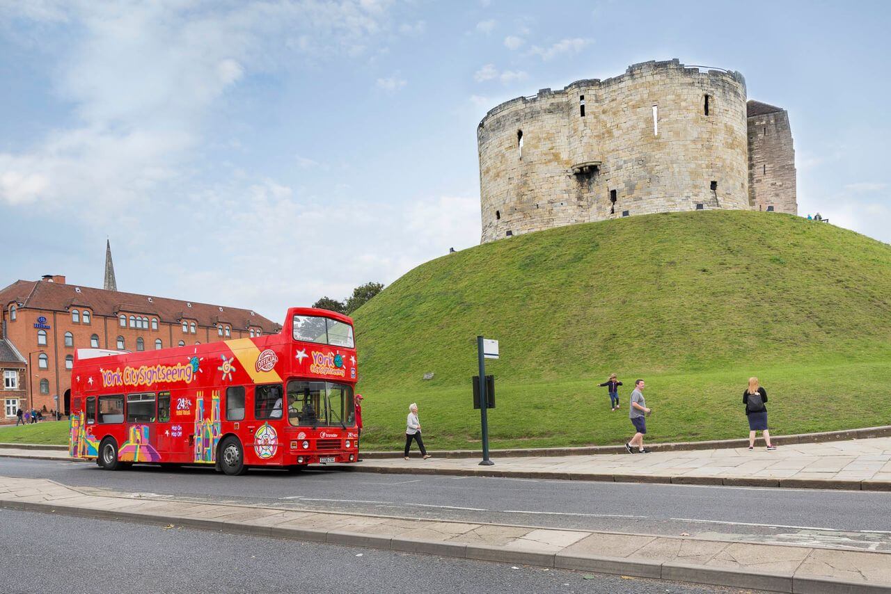 CitySightseeing hop-on hop-off double-decker tour bus parked near Clifford's Tower