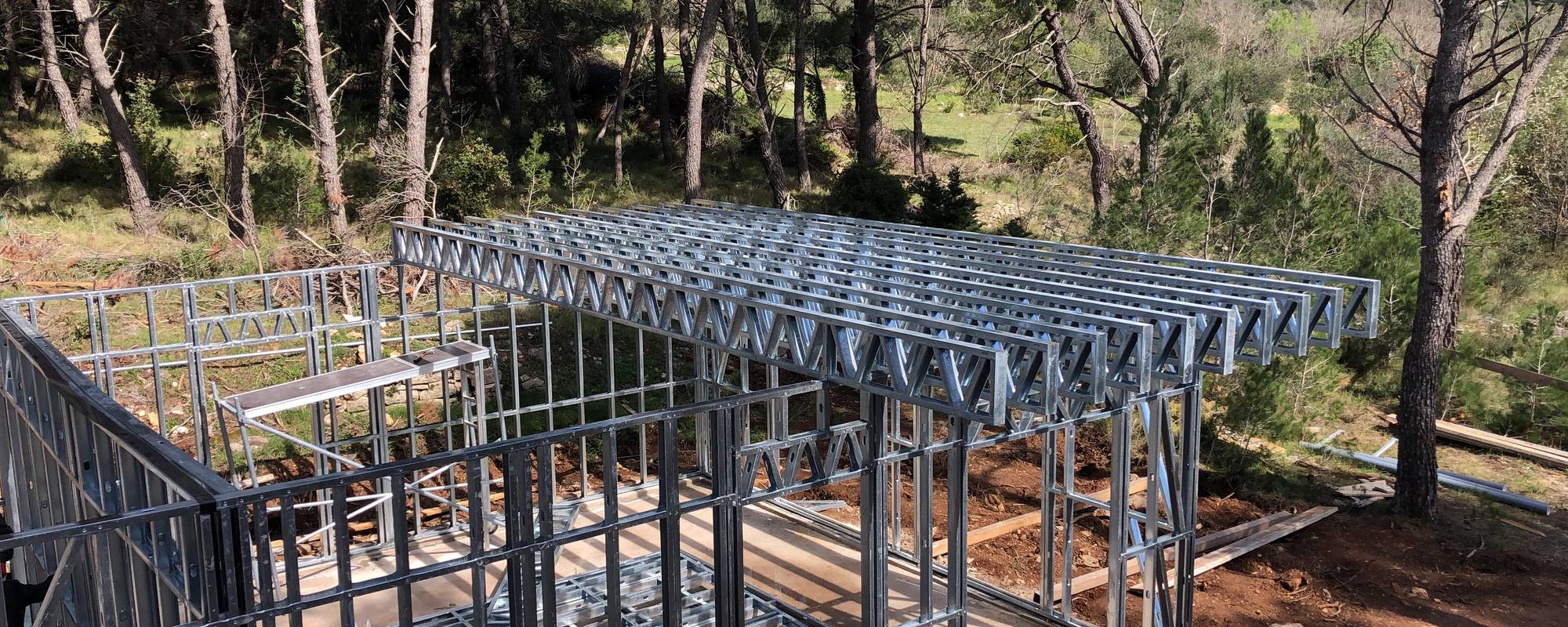 Close-up of steel house framing for a new home in a natural setting.