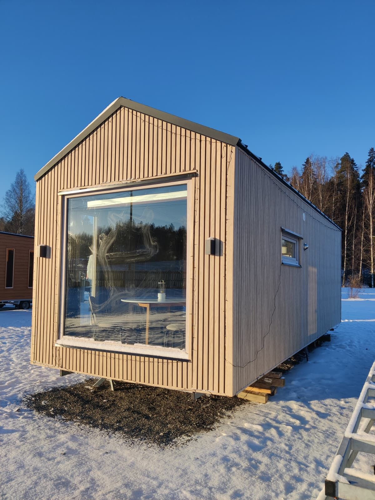 Compact steel structure cabin in a snowy outdoor landscape.