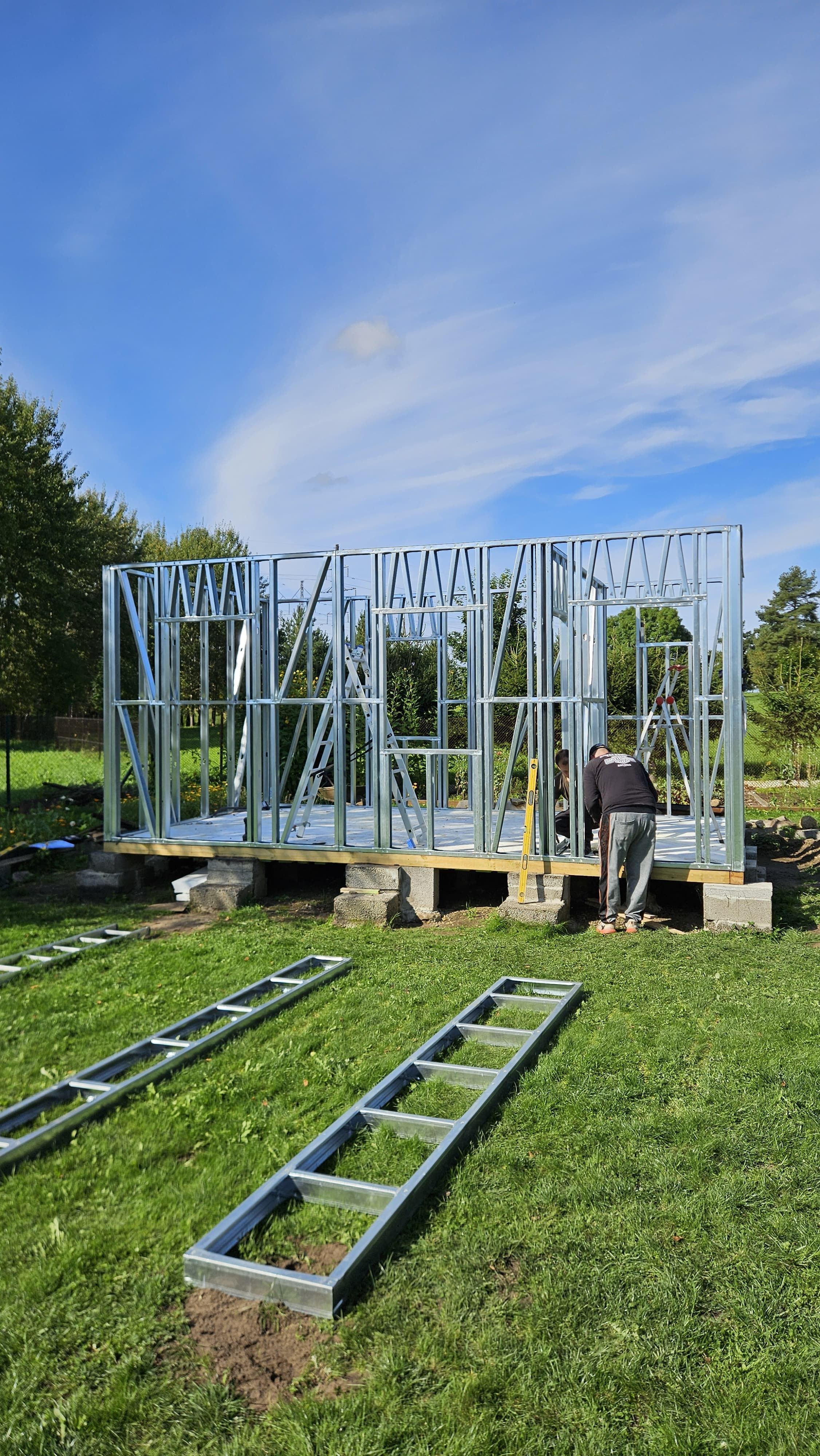 Steel house framing for a custom residential build in a natural setting.