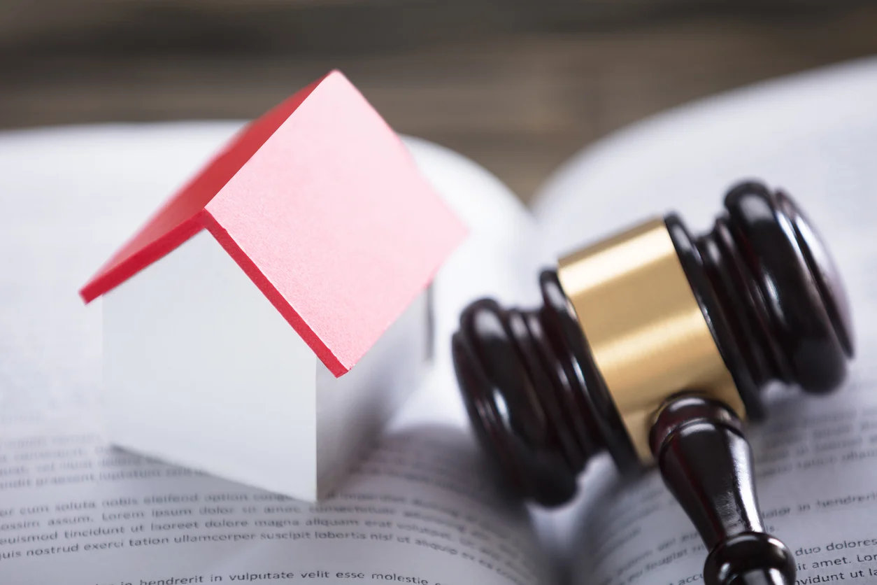 close-up-of-house-model-with-red-roof-and-gavel-on-law-book.webp