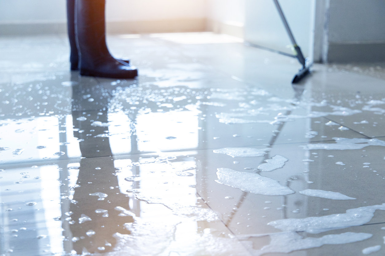 Janitor squeegee water on the floor hallway office building or walkway after school and classroom work job with sun light background.