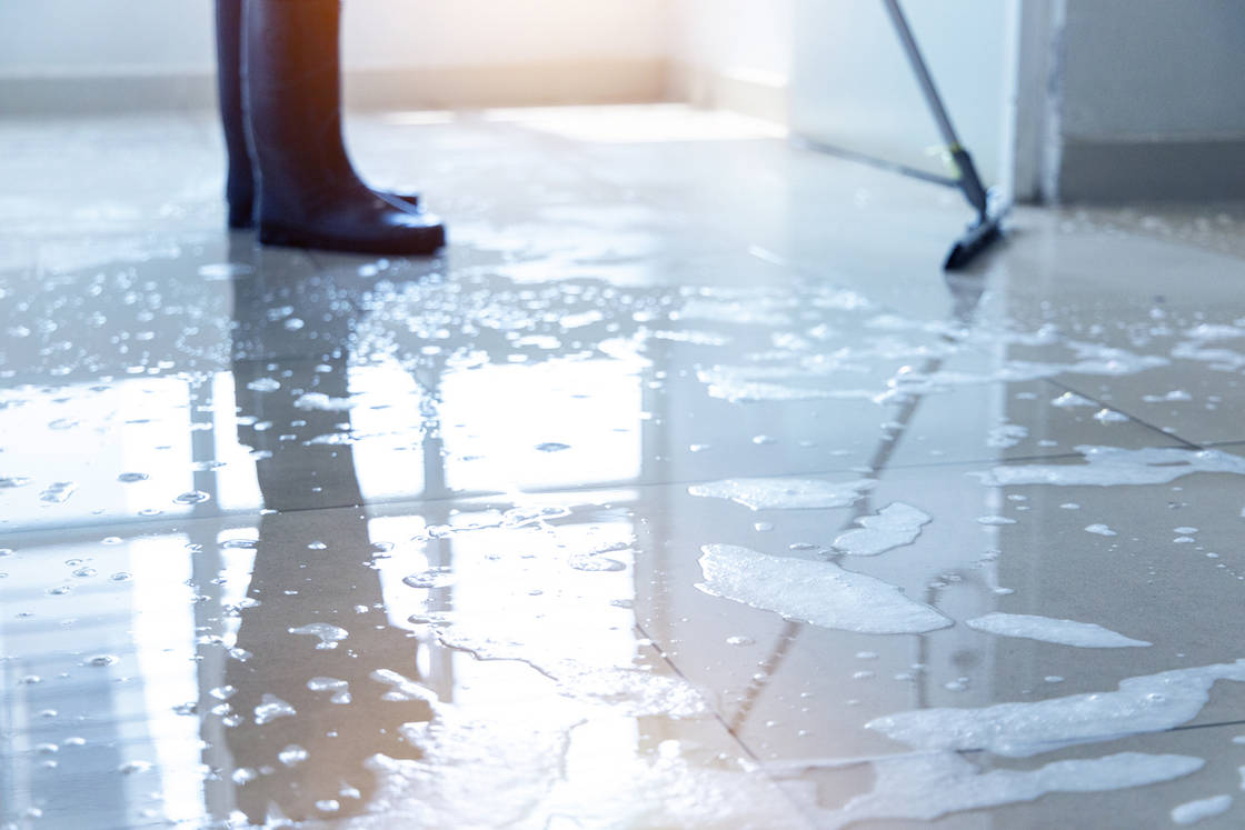 Janitor squeegee water on the floor hallway office building or walkway after school and classroom work job with sun light background.