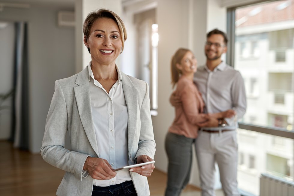 portrait-female-real-estate-agent-looking-camera-while-happy-couple-standing-background_rBuYP8D9TK.jpg