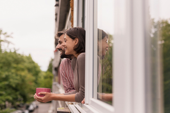 A Happy Couple looking out the window with a coffee