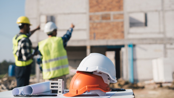 Structural engineer and architect working with blueprints at the outdoors construction site.