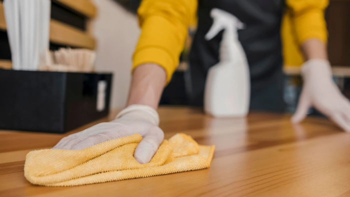 a man wearing gloves cleaning a table with a cloth