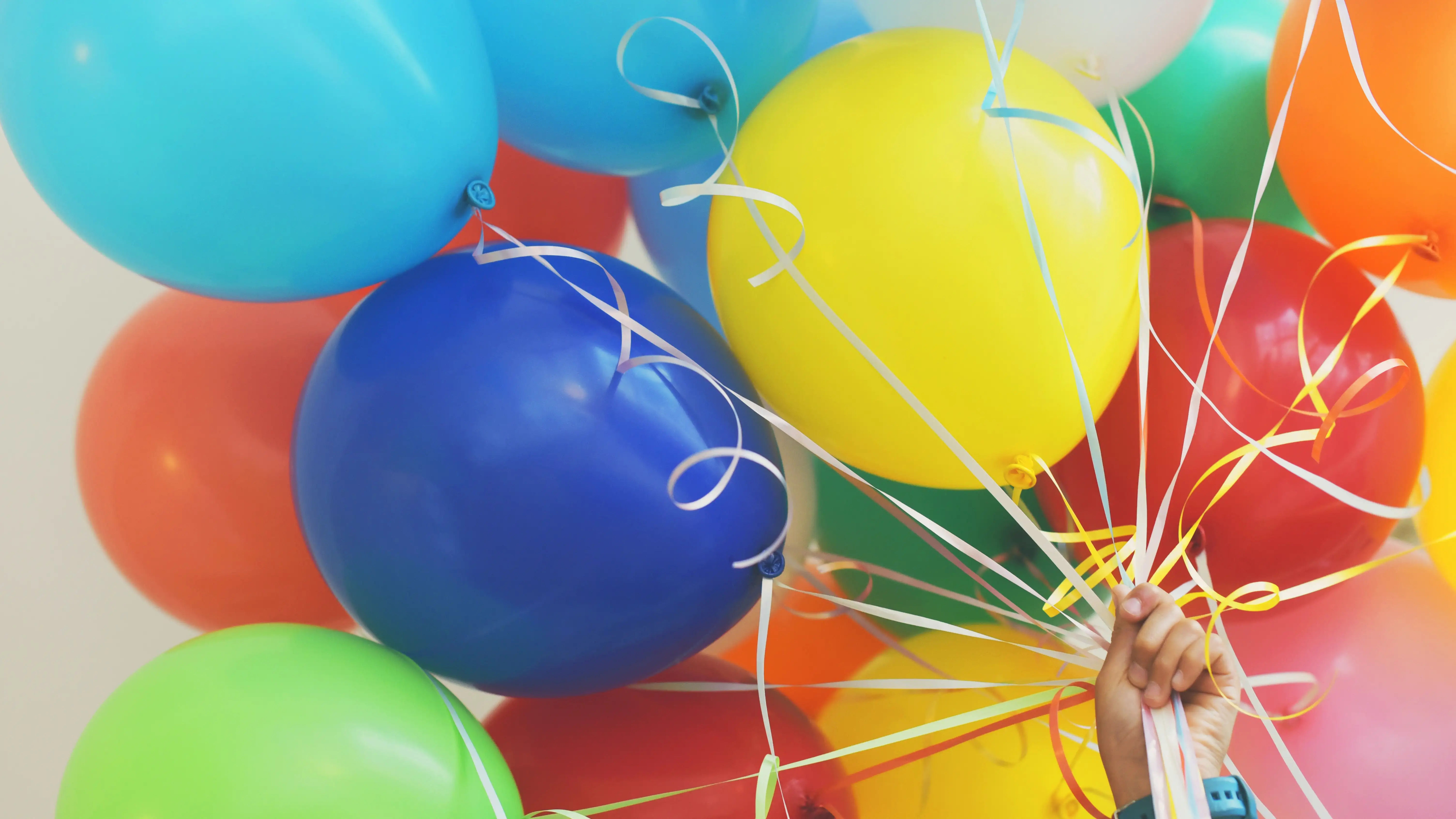 diversos balões coloridos sendo segurados por uma pessoa