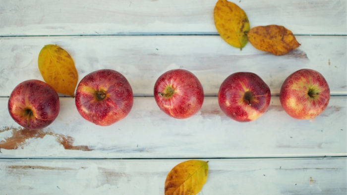 five diferent apples on a white table