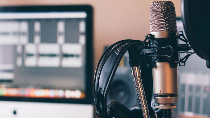 headphone next to a microphone and a laptop in the background