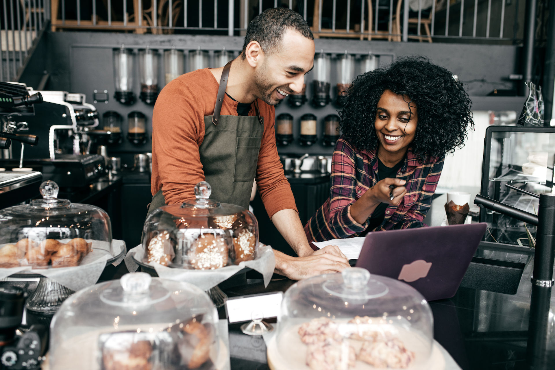 Happy coffee shop owners reviewing information on a computer