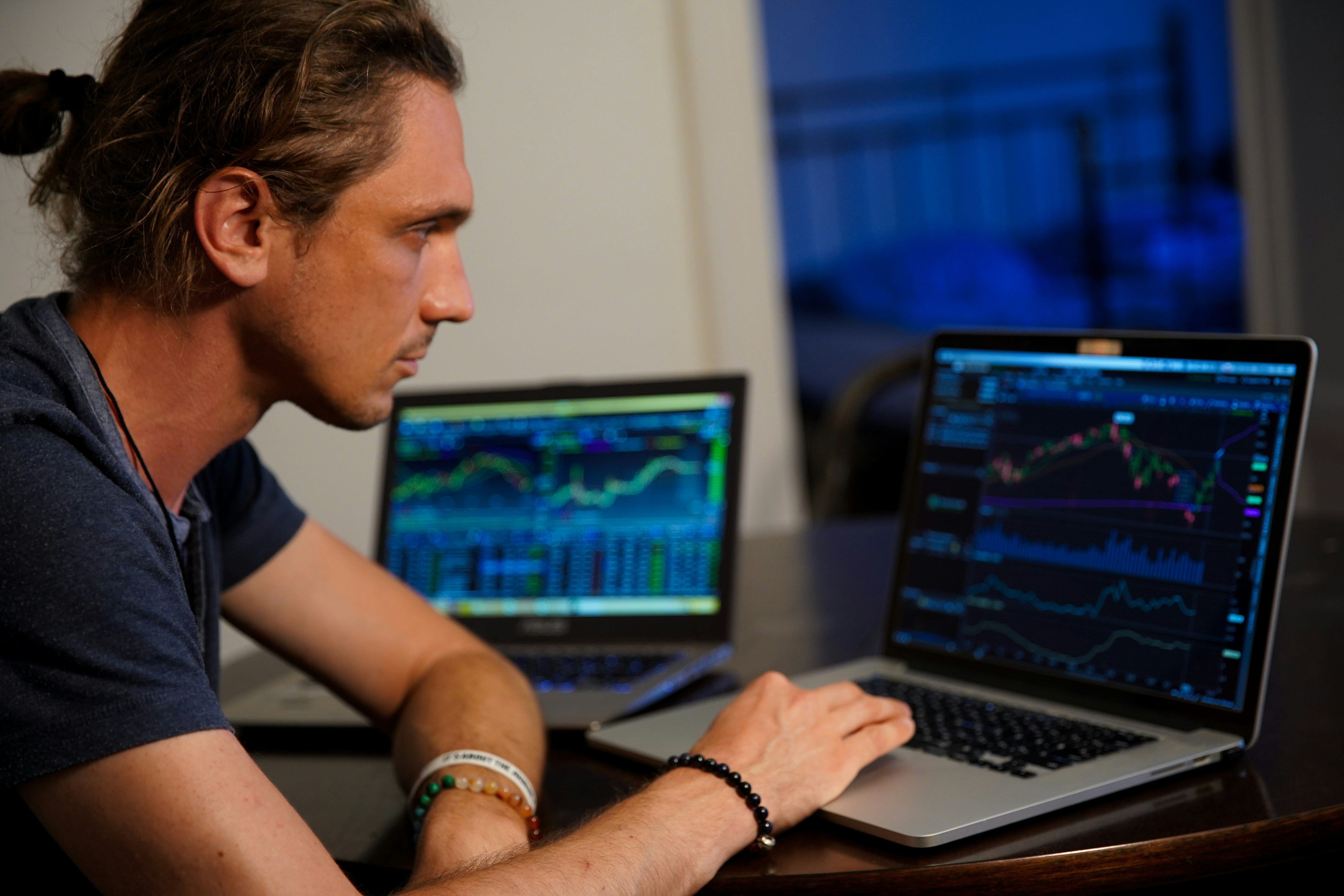 A person sitting at a kitchen table surrounded by bills, looking at their phone for financial options
