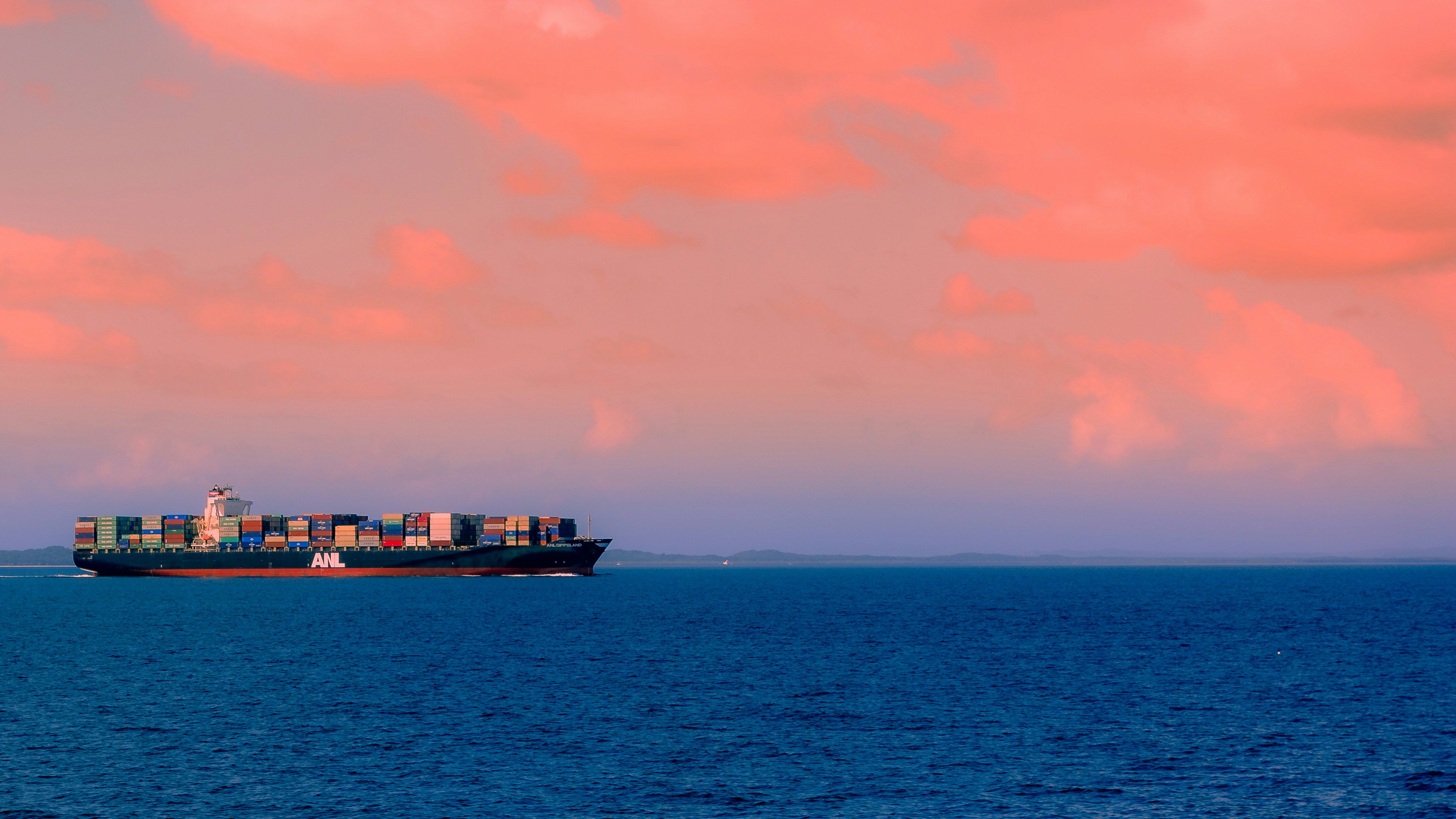 A large cargo tanker vessel crossing calm open ocean waters under clear blue skies, representing commercial maritime shipping through international trade routes