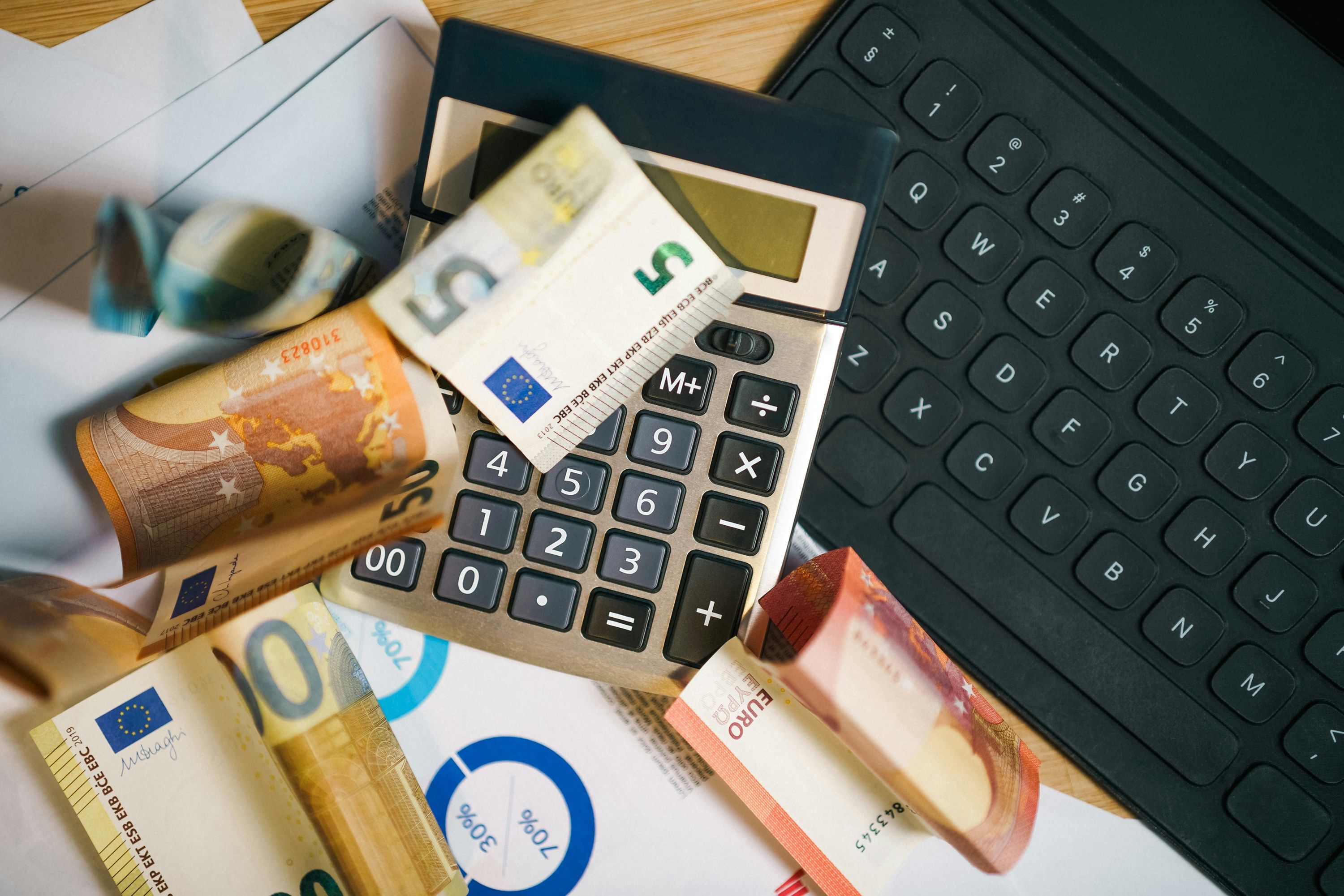 A person using a laptop and financial planning tools to calculate retirement contributions