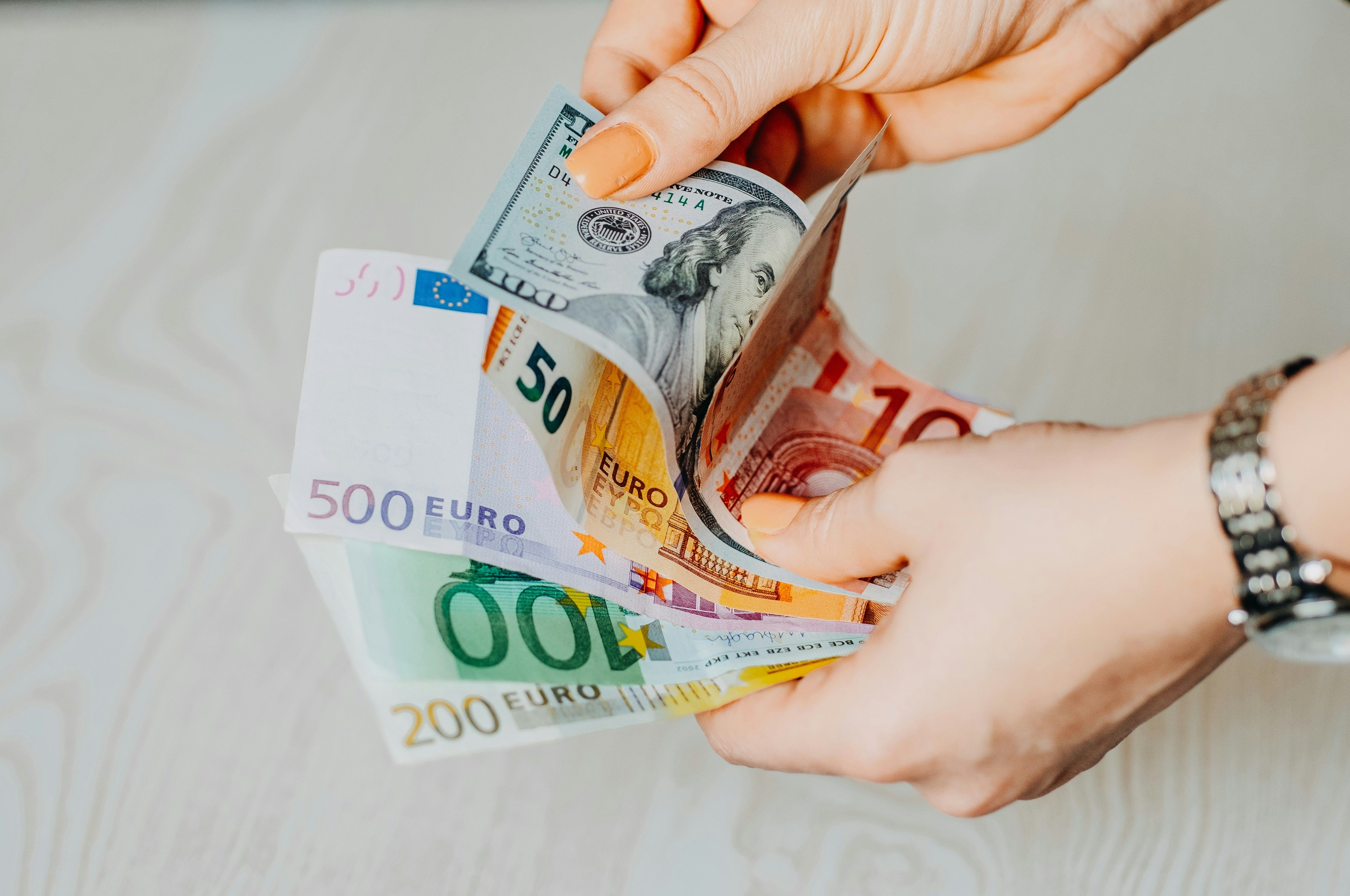 A person organizing cash into three separate envelopes on a wooden table