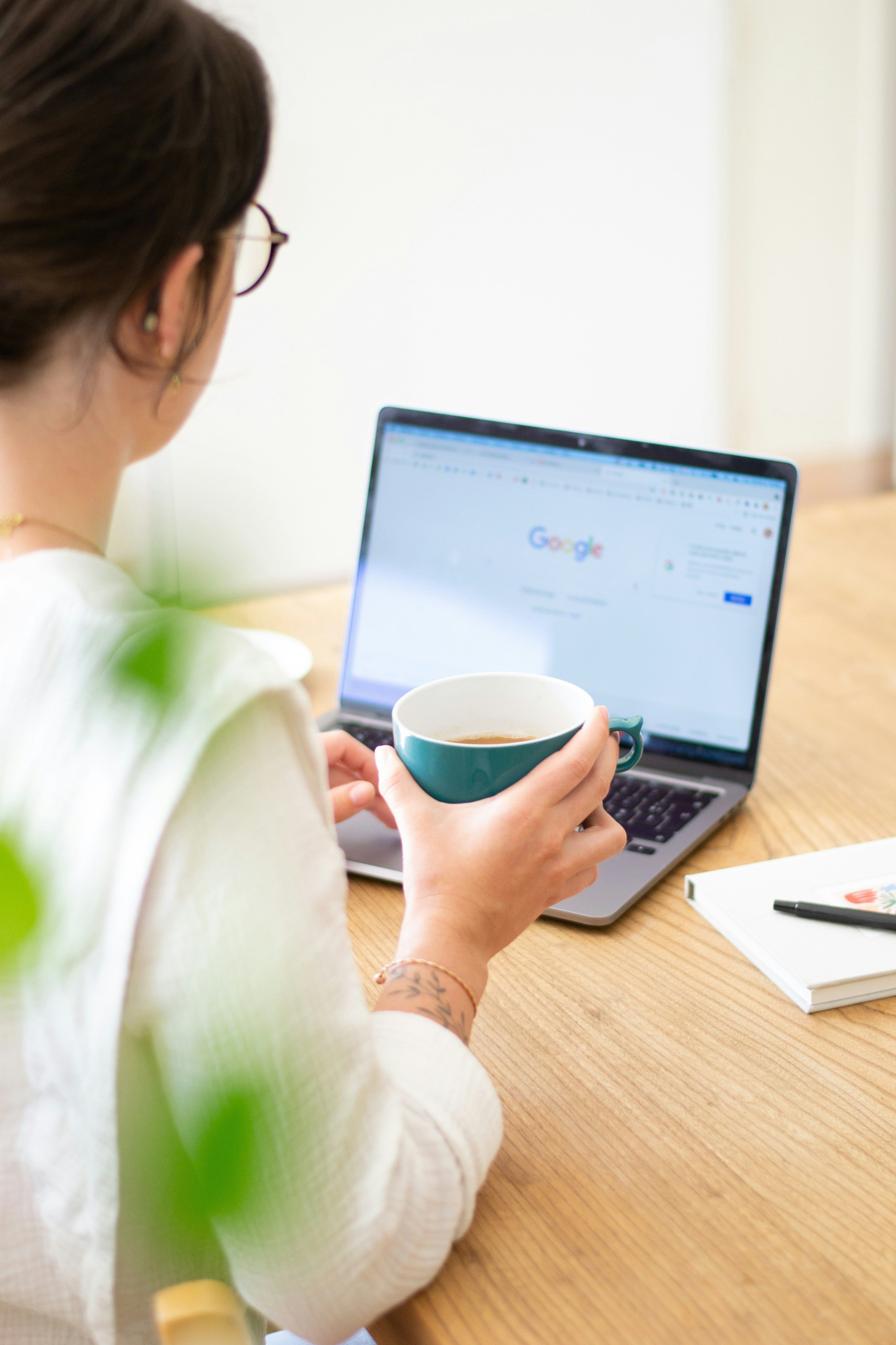 A freelancer working on a laptop at a clean desk with coffee and notebook nearby