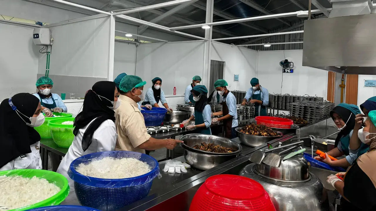Seorang kepala Satuan Pelayanan Pemenuhan Gizi mengawasi proses memasak di dapur.