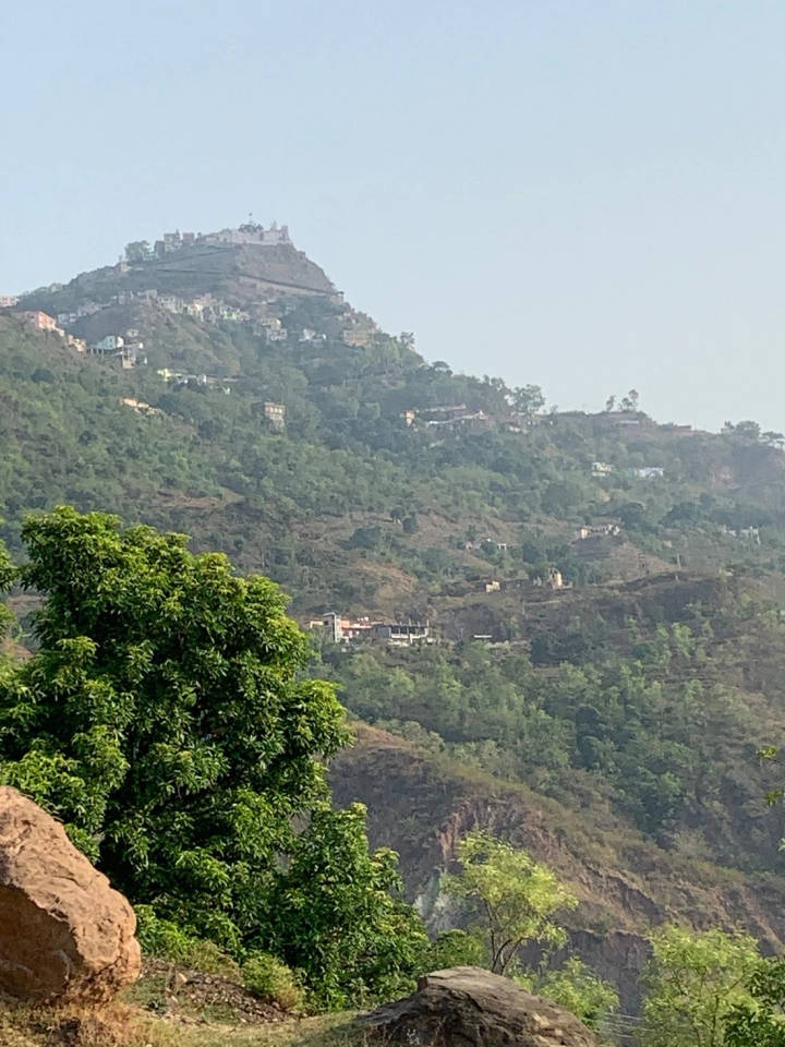Naina Devi temple on its hilltop, with houses on the green slopes below