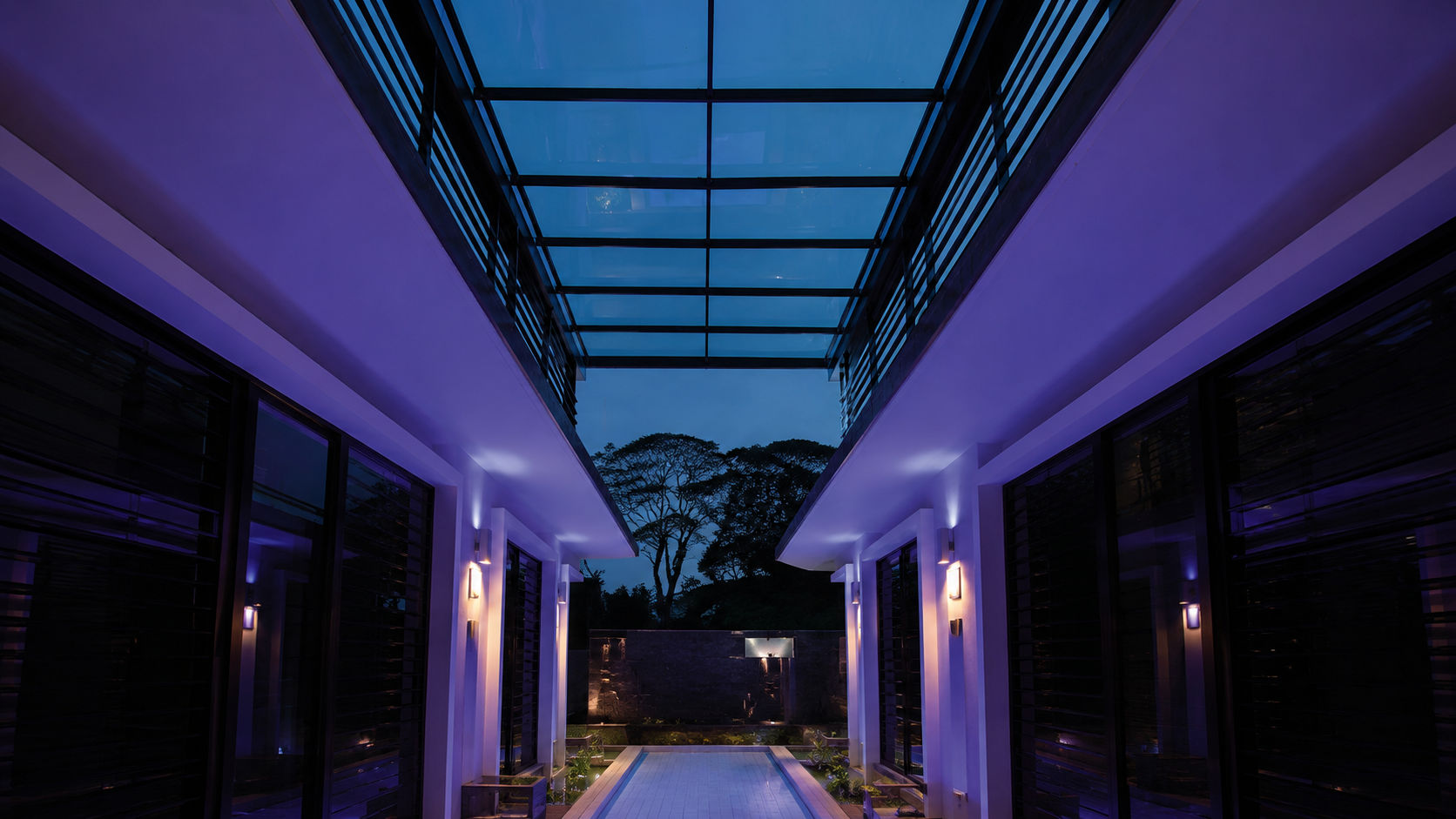 Tettro glass roof spanning a modern courtyard at twilight