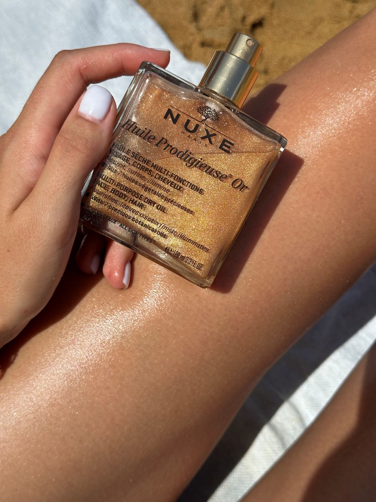 NUXE body oil photographed in warm coastal light