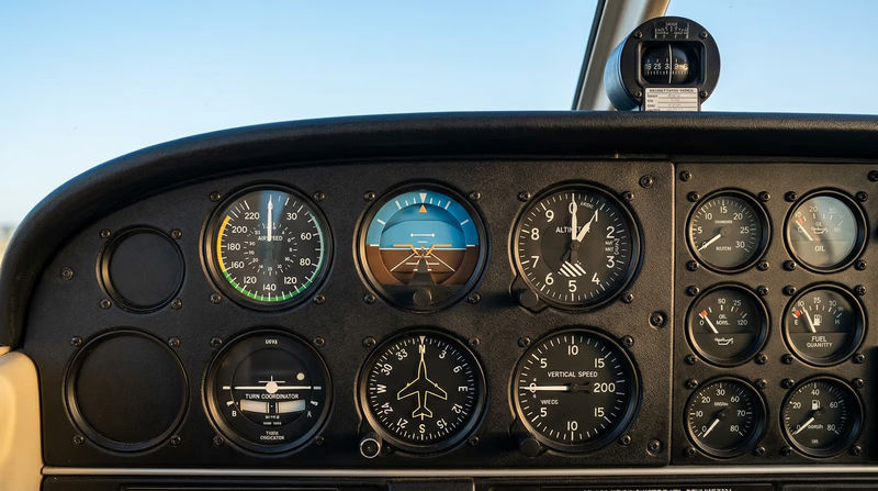 A clean illustration of a single-engine aircraft instrument panel showing the six-pack arrangement of flight instruments with each gauge clearly visible and labeled